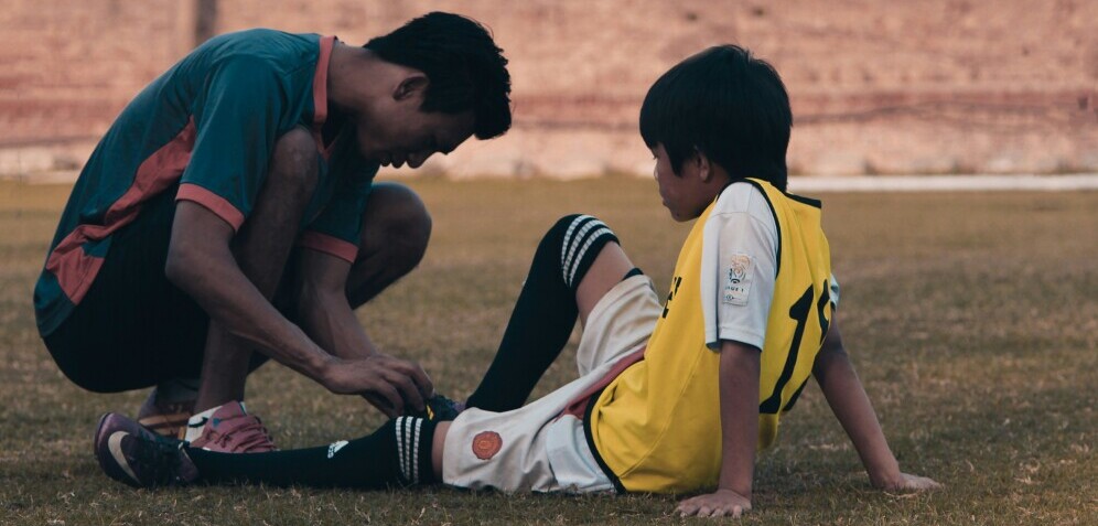 a coach examining an injured soccer player