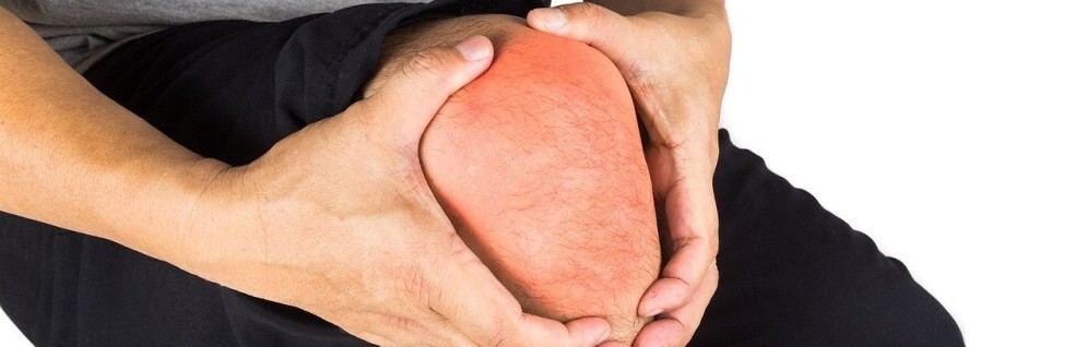 a man holding an injured knee that has crossed his pain threshold