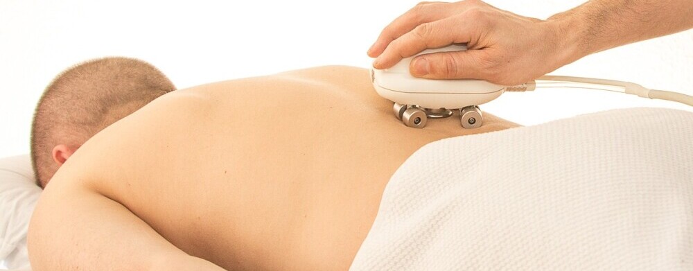 a man laying face down while a massage therapist works on his back